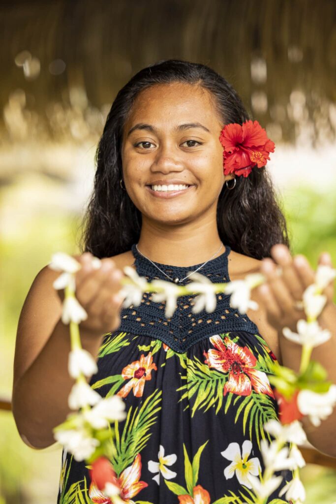 young tahitian lady offering a flower lei