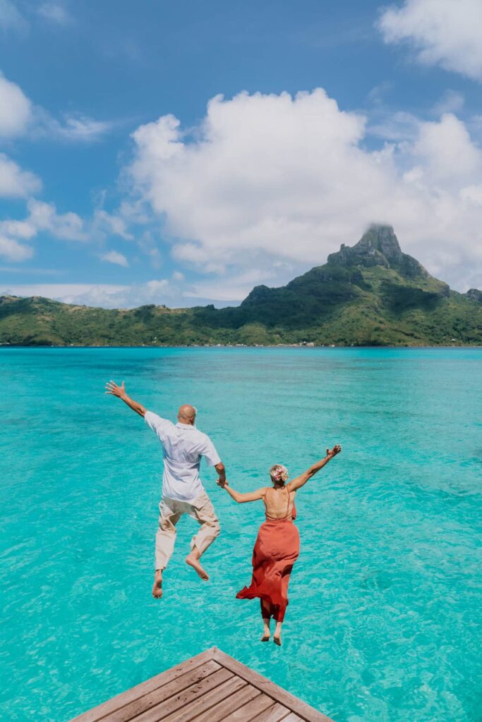 Couple jumping off a bungalow with moutain view in Bora Bora