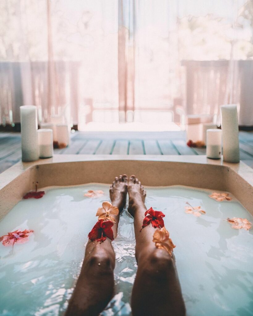 Girl taking a bath in the OVERWATER SPA SUITE at the Four Seasons Bora Bora