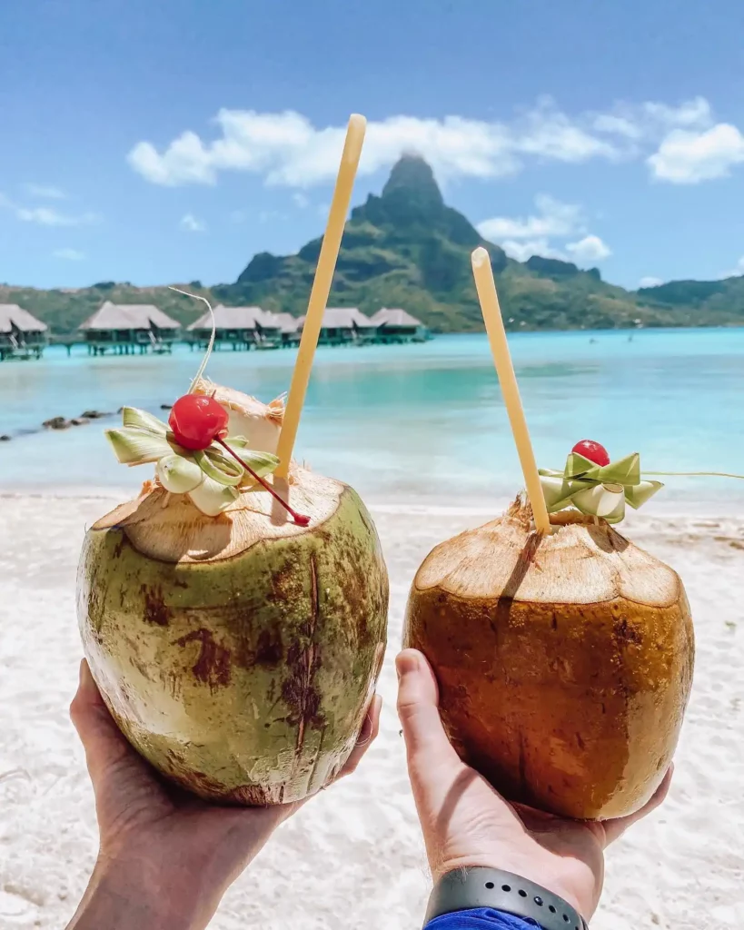 two coconut cocktails with bora bora mountain on the background